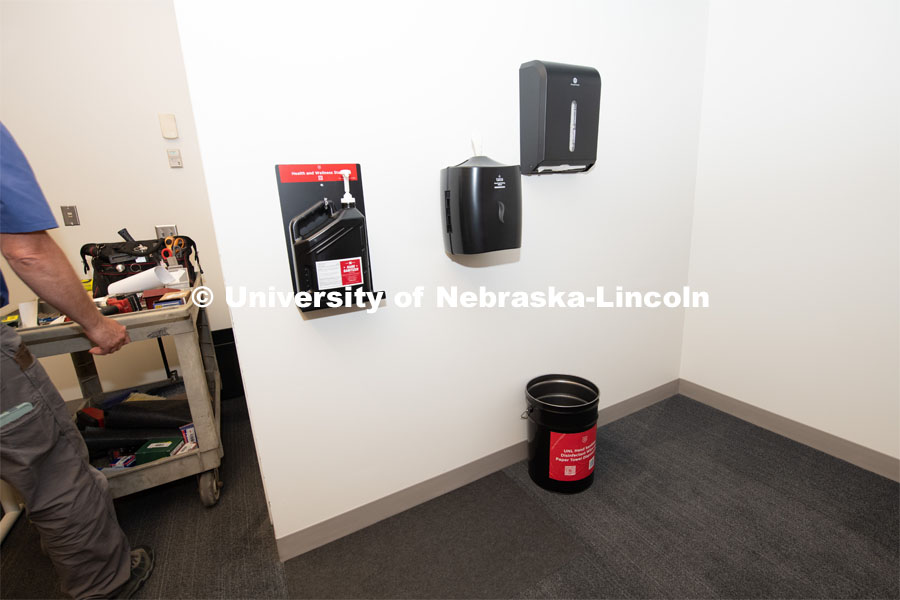 Building Systems Maintenance technicians install hand sanitizer, disinfectant wipes, paper towels, trash cans and floor coverings in classrooms across campus. August 11, 2020. Photo by Gregory Nathan / University Communication.